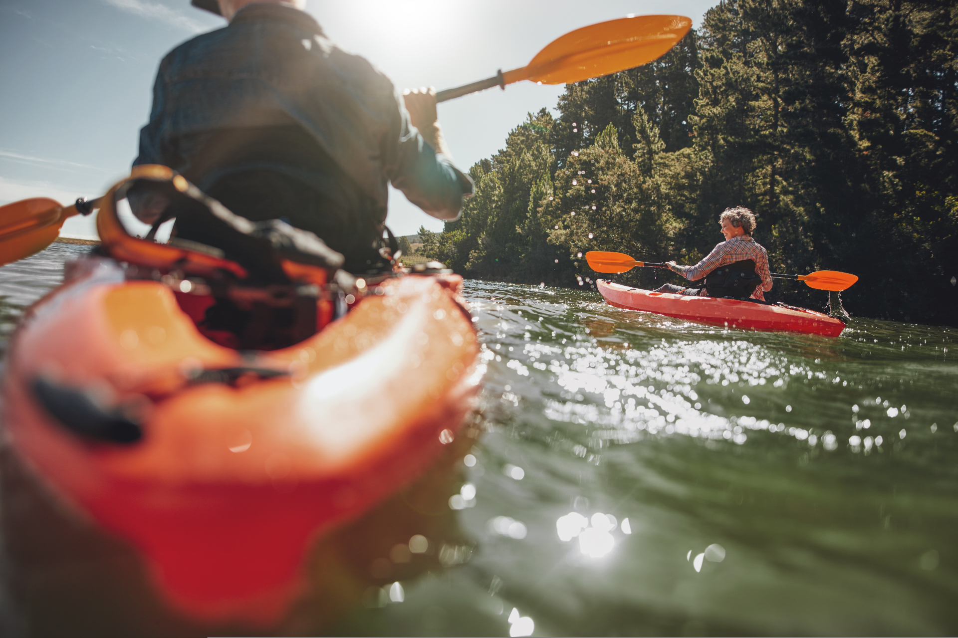 Two members kayaking on a sunlit lake